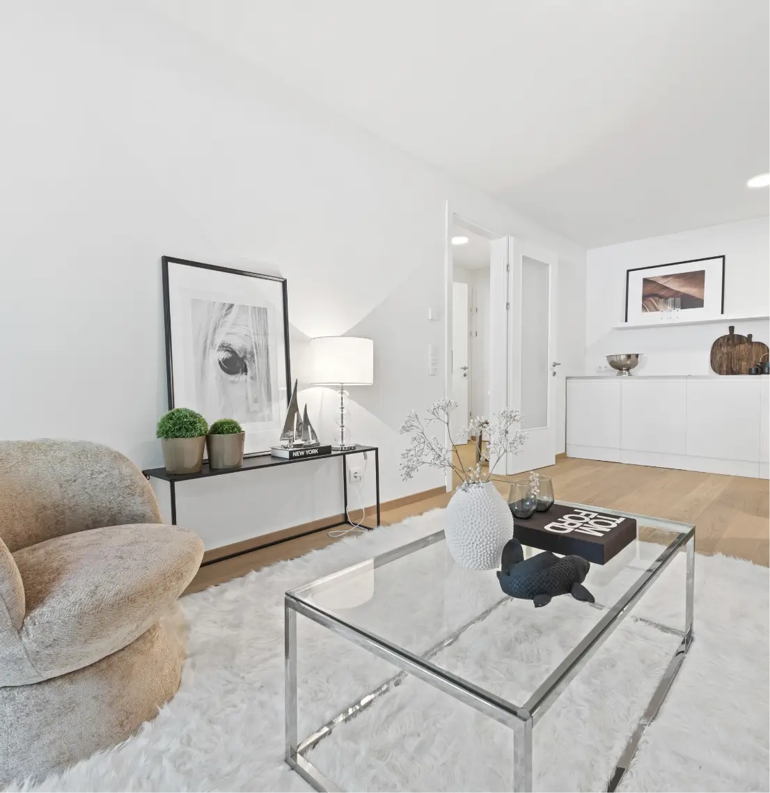 Stylisher Wohnbereich mit modernem Sessel, Couchtisch aus Glas und weißem Teppich.