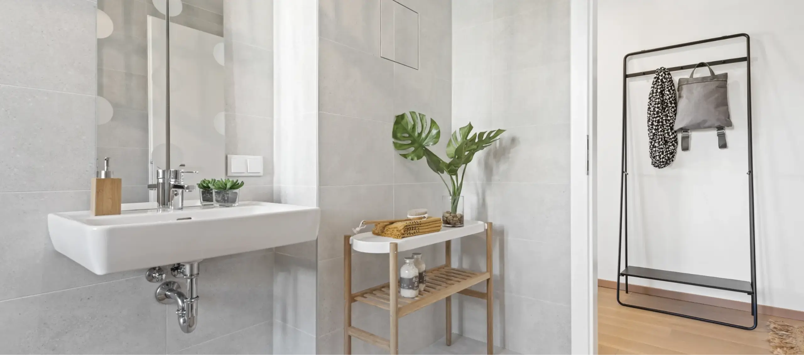 Modernes Badezimmer mit hellem Fliesenboden, quadratischem Waschbecken und Pflanzen.