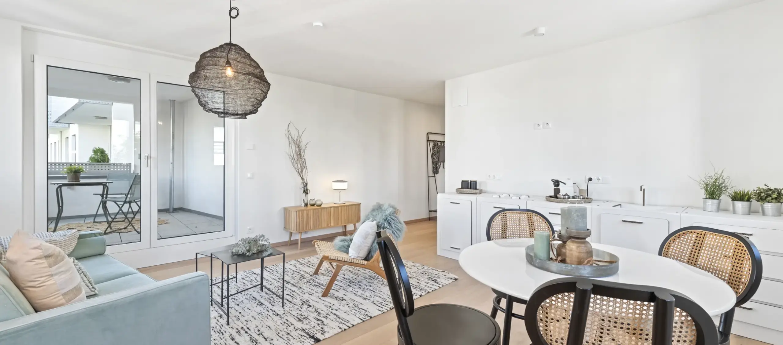 Heller, moderner Wohn- und Essbereich mit integrierter Küchenzeile und Balkon.