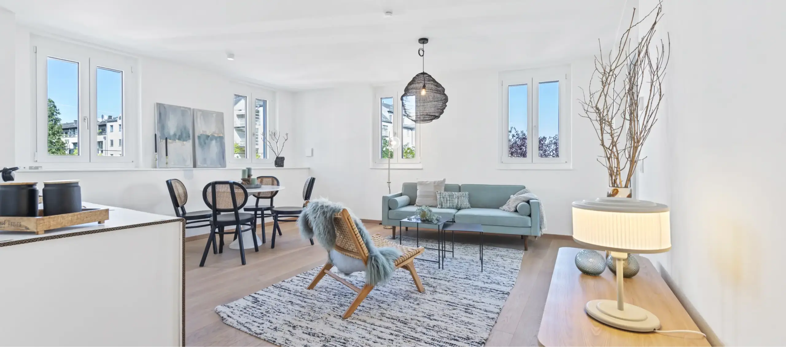 Großzügiger, heller Wohnbereich mit Essbereich, Couch, Sesseln und vielen Fenstern.