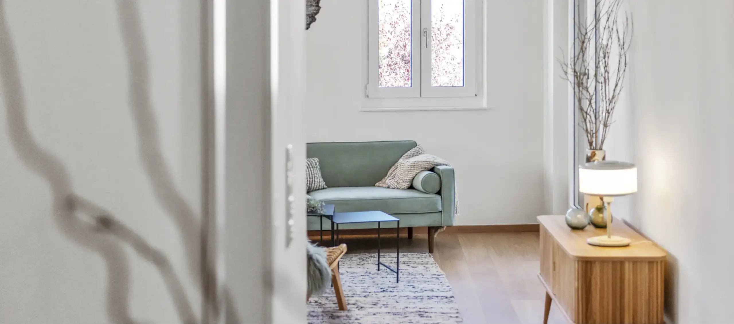 Gemütliches, modernes Wohnzimmer mit hellgrünem Sofa und Holzboden.